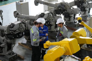 Robot mühendisleri fabrika deposunda robotik kolun bakımı üzerinde çalışıyorlar. İş teknolojisi.