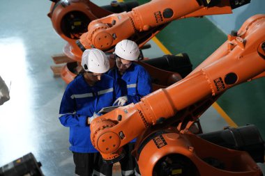 Robot mühendisleri fabrika deposunda robotik kolun bakımı üzerinde çalışıyorlar. İş teknolojisi.