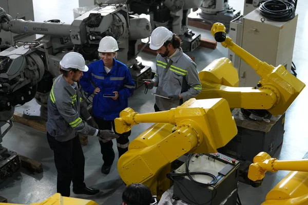 stock image Robotics engineers working on maintenance of robotic arm in factory warehouse. Business technology.