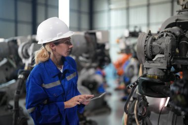 Robot mühendisi fabrika deposunda robotik kolun bakımı üzerinde çalışıyor. İş teknolojisi.