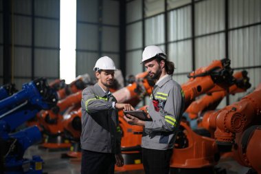 Robot mühendisleri fabrika deposunda robotik kolun bakımı üzerinde çalışıyorlar. İş teknolojisi.