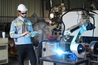 Robot mühendisi fabrika deposunda robotik kolun bakımı üzerinde çalışıyor. İş teknolojisi.