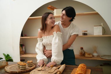 Genç ve güzel bir çift yemek pişiriyor ve gülümsüyor.. 