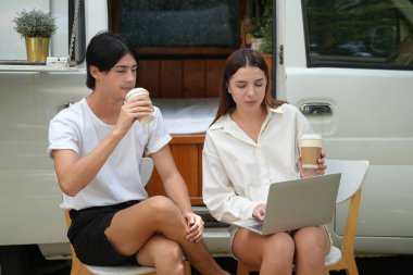 Genç insanlar dizüstü bilgisayara bakıyor ve kahve içiyor. 