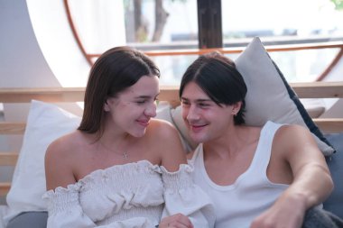 Birbirine aşık çiftler yatak odasında oturuyor. Mutlu genç çift romantik anların tadını çıkarıyor.. 