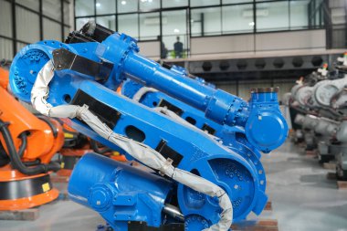 Teknisyen bir robot kolu dijital tabletle programlar ve bir fabrikada robot montajı yapar. Çırak mühendisleri fabrikada robot programlıyorlar..