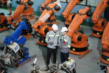 Robot mühendisleri fabrika deposunda robotik kolun bakımı üzerinde çalışıyorlar. İş teknolojisi.