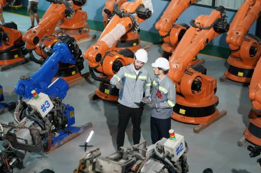 Robot mühendisleri fabrika deposunda robotik kolun bakımı üzerinde çalışıyorlar. İş teknolojisi.