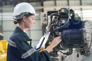 Teknisyen bir robot kolu dijital tabletle programlar ve bir fabrikada robot montajı yapar. Çırak mühendisleri fabrikada robot programlıyorlar..