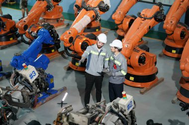 Robot mühendisleri fabrika deposunda robotik kolun bakımı üzerinde çalışıyorlar. İş teknolojisi.