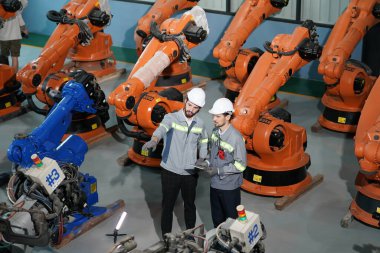 Robot mühendisleri fabrika deposunda robotik kolun bakımı üzerinde çalışıyorlar. İş teknolojisi.