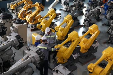 Robot mühendisleri fabrika deposunda robotik kolun bakımı üzerinde çalışıyorlar. İş teknolojisi.