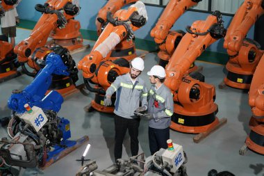 Robot mühendisleri fabrika deposunda robotik kolun bakımı üzerinde çalışıyorlar. İş teknolojisi.