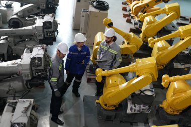 Robot mühendisleri fabrika deposunda robotik kolun bakımı üzerinde çalışıyorlar. İş teknolojisi.