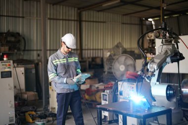 Robot mühendisi fabrika deposunda robotik kolun bakımı üzerinde çalışıyor. İş teknolojisi.