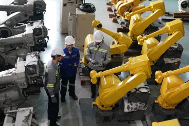 Robot mühendisleri fabrika deposunda robotik kolun bakımı üzerinde çalışıyorlar. İş teknolojisi.