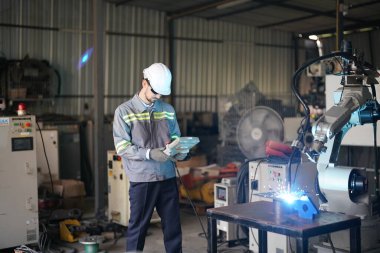 Robot mühendisi fabrika deposunda robotik kolun bakımı üzerinde çalışıyor. İş teknolojisi.