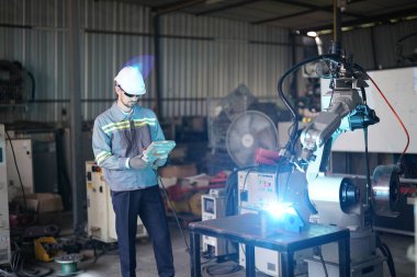 Robot mühendisi fabrika deposunda robotik kolun bakımı üzerinde çalışıyor. İş teknolojisi.