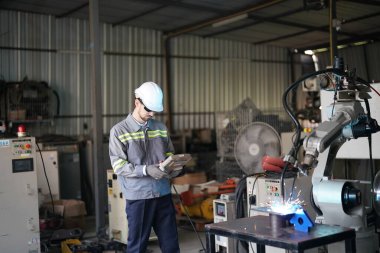 Robot mühendisi fabrika deposunda robotik kolun bakımı üzerinde çalışıyor. İş teknolojisi.