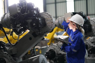 Robot mühendisi fabrika deposunda robotik kolun bakımı üzerinde çalışıyor. İş teknolojisi.