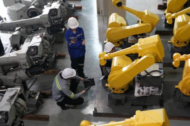Robot mühendisleri fabrika deposunda robotik kolun bakımı üzerinde çalışıyorlar. İş teknolojisi.