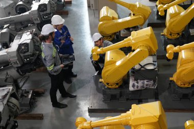 Robot mühendisleri fabrika deposunda robotik kolun bakımı üzerinde çalışıyorlar. İş teknolojisi.