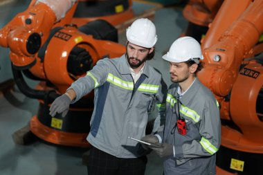 Robot mühendisleri fabrika deposunda robotik kolun bakımı üzerinde çalışıyorlar. İş teknolojisi.