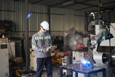 Robot mühendisi fabrika deposunda robotik kolun bakımı üzerinde çalışıyor. İş teknolojisi.