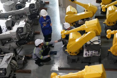 Robot mühendisleri fabrika deposunda robotik kolun bakımı üzerinde çalışıyorlar. İş teknolojisi.