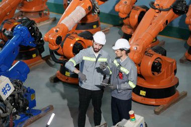 Robot mühendisleri fabrika deposunda robotik kolun bakımı üzerinde çalışıyorlar. İş teknolojisi.