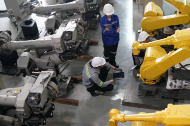 Robot mühendisleri fabrika deposunda robotik kolun bakımı üzerinde çalışıyorlar. İş teknolojisi.