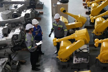 Robot mühendisleri fabrika deposunda robotik kolun bakımı üzerinde çalışıyorlar. İş teknolojisi.