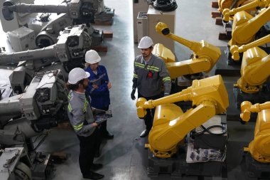 Robot mühendisleri fabrika deposunda robotik kolun bakımı üzerinde çalışıyorlar. İş teknolojisi.