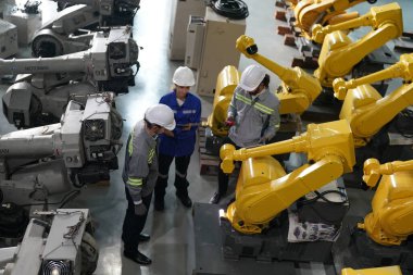 Robot mühendisleri fabrika deposunda robotik kolun bakımı üzerinde çalışıyorlar. İş teknolojisi.