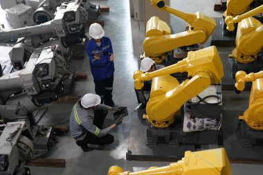 Robot mühendisleri fabrika deposunda robotik kolun bakımı üzerinde çalışıyorlar. İş teknolojisi.