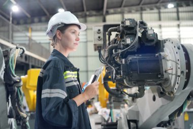 Teknisyen bir robot kolu dijital tabletle programlar ve bir fabrikada robot montajı yapar. Çırak mühendisleri fabrikada robot programlıyorlar..
