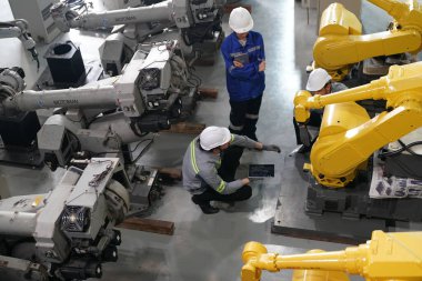 Robot mühendisleri fabrika deposunda robotik kolun bakımı üzerinde çalışıyorlar. İş teknolojisi.