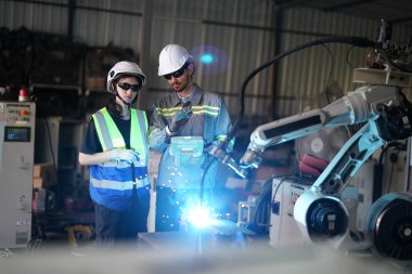 Robot mühendisleri fabrika deposunda robotik kolun bakımı üzerinde çalışıyorlar. İş teknolojisi.