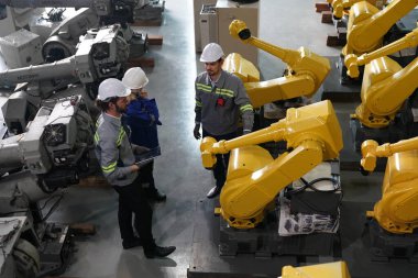 Robot mühendisleri fabrika deposunda robotik kolun bakımı üzerinde çalışıyorlar. İş teknolojisi.