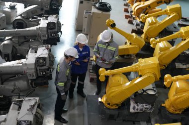 Robot mühendisleri fabrika deposunda robotik kolun bakımı üzerinde çalışıyorlar. İş teknolojisi.