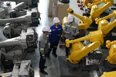 Robot mühendisleri fabrika deposunda robotik kolun bakımı üzerinde çalışıyorlar. İş teknolojisi.