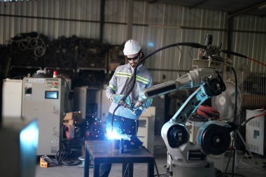 Robot mühendisi fabrika deposunda robotik kolun bakımı üzerinde çalışıyor. İş teknolojisi.