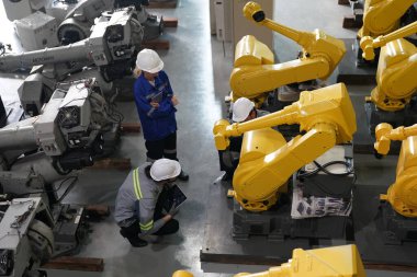 Robot mühendisleri fabrika deposunda robotik kolun bakımı üzerinde çalışıyorlar. İş teknolojisi.