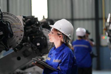 Robot mühendisi fabrika deposunda robotik kolun bakımı üzerinde çalışıyor. İş teknolojisi.