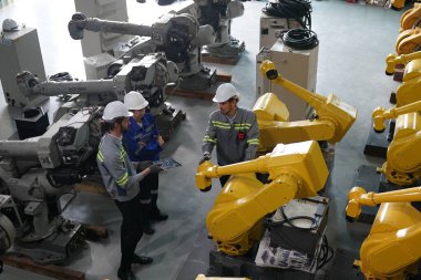 Robot mühendisleri fabrika deposunda robotik kolun bakımı üzerinde çalışıyorlar. İş teknolojisi.
