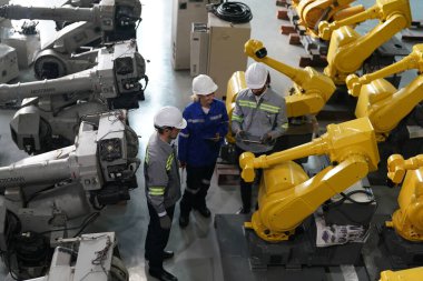 Robot mühendisleri fabrika deposunda robotik kolun bakımı üzerinde çalışıyorlar. İş teknolojisi.