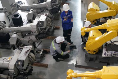 Robot mühendisleri fabrika deposunda robotik kolun bakımı üzerinde çalışıyorlar. İş teknolojisi.