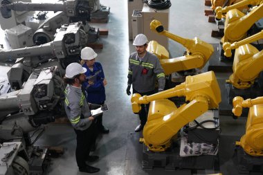 Robot mühendisleri fabrika deposunda robotik kolun bakımı üzerinde çalışıyorlar. İş teknolojisi.