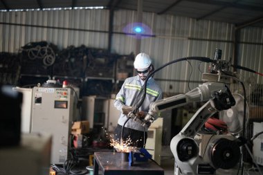 Robot mühendisi fabrika deposunda robotik kolun bakımı üzerinde çalışıyor. İş teknolojisi.