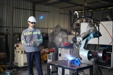Robot mühendisi fabrika deposunda robotik kolun bakımı üzerinde çalışıyor. İş teknolojisi.